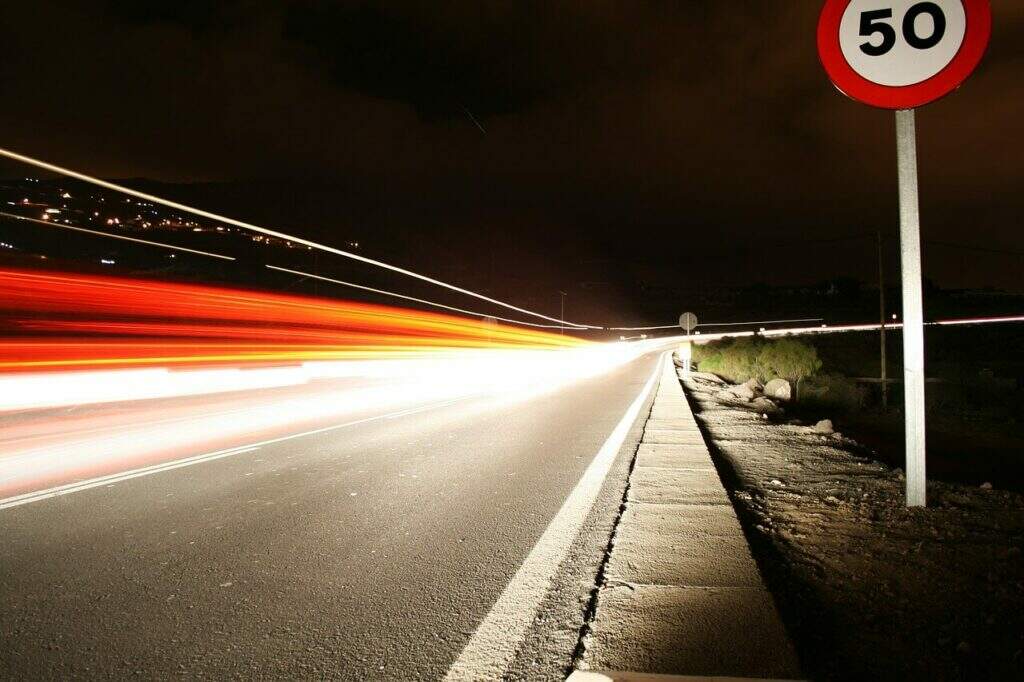 asfalto com placa de trânsito e luz que indica veículo passando em alta velocidade