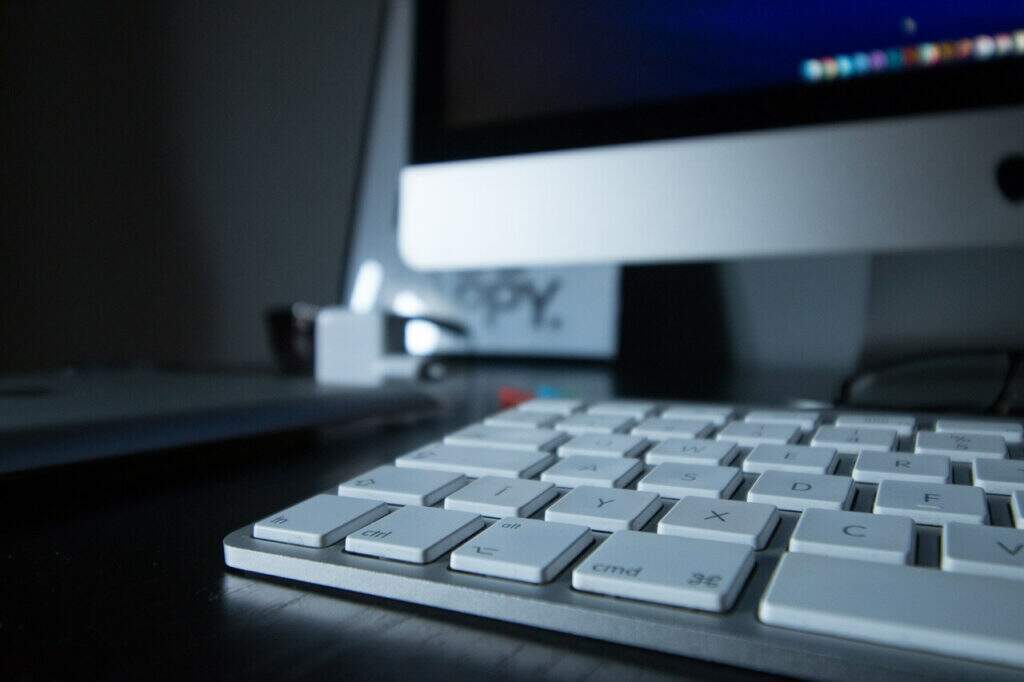 Um teclado está posicionado na frente de um computador